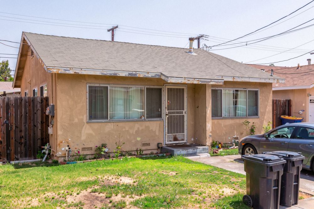 Lived-in 1960s stucco ranch house with a patchy lawn